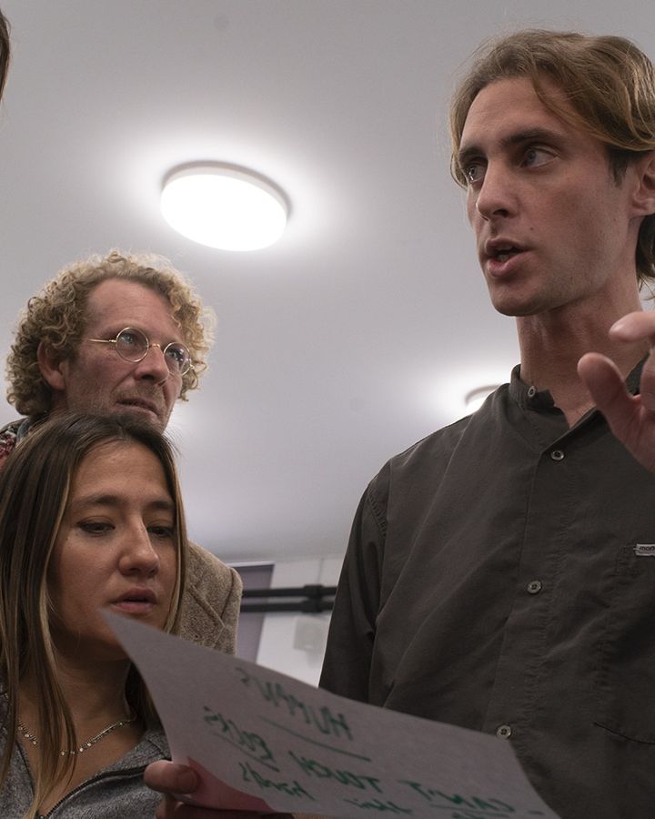 Participantes debatiendo de pie con una hoja en la mano