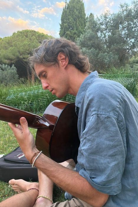 Javi tocando la guitarra sentado en el césped